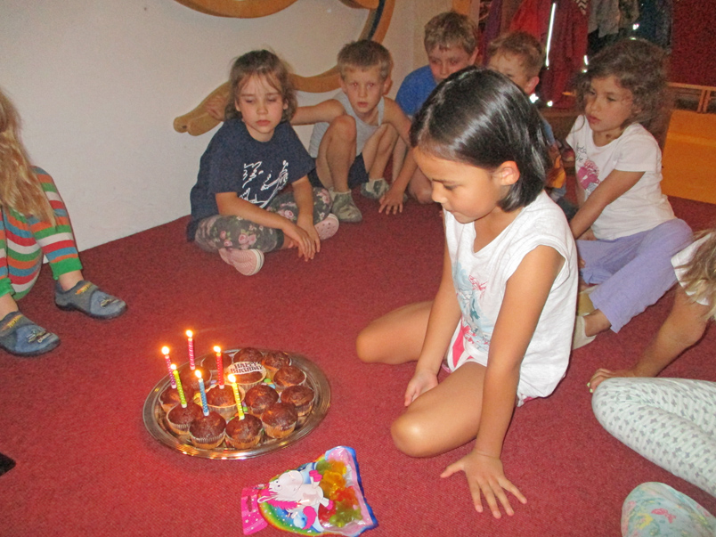 Kinder sitzen um einen Teller mit Geburtstags-Muffins