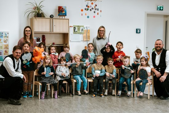Gruppenbild mit Erzieherinnen, Handwerkern und vielen Kindern im Gruppenraum