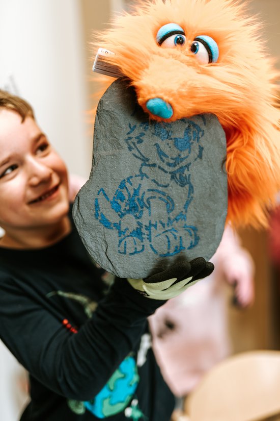 Orangenes Kuscheltier mit Schieferplatte