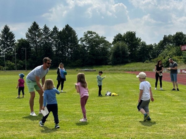 Kinder und Erwachsene auf einem Rasenplatz