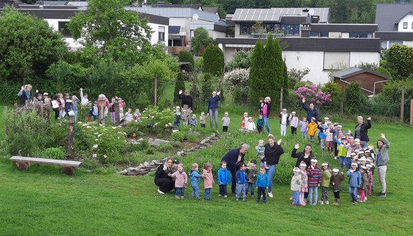 Viele Kinder auf einer großen Wiese mit Kräuterbeet