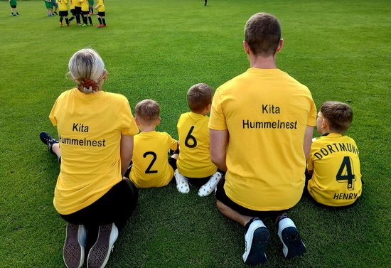 Zwei große und 3 kleine Sportler im gelben Trikot