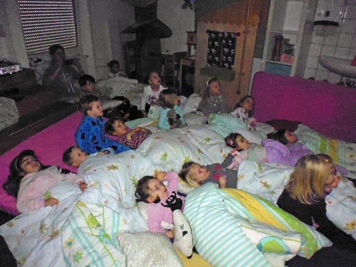 Viele wache Kinder liegen mit Bettzeug im "Riesenbett"