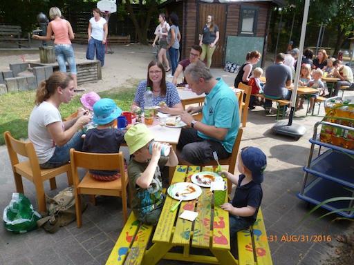 Kinder und Erwachsene sitzen essend am Tisch