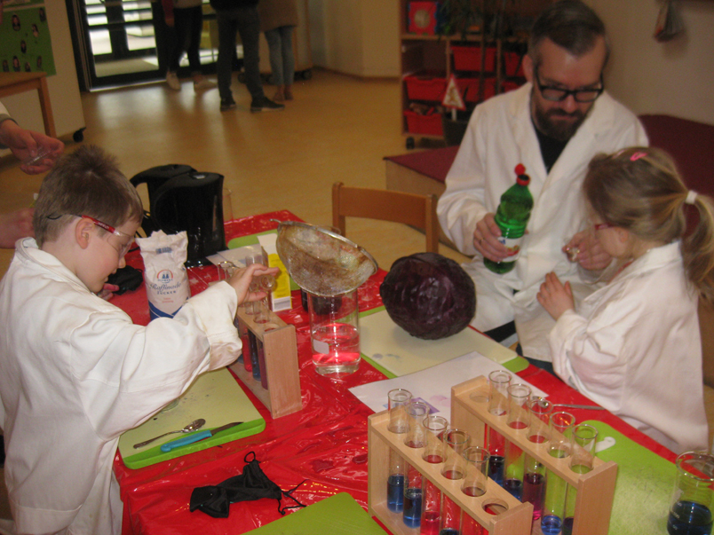 Chemielehrer und Kinder am Tisch mit dem Experiment