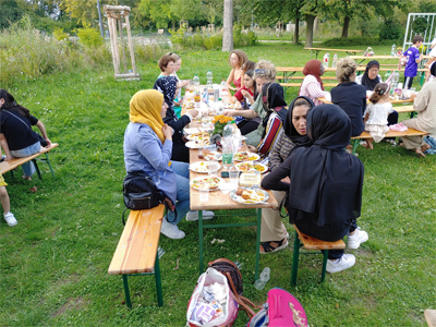 Viele Gäste sitzen an Tischen auf einer Rasenfläche