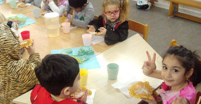 Kinder sitzen am Tisch und essen Waffeln