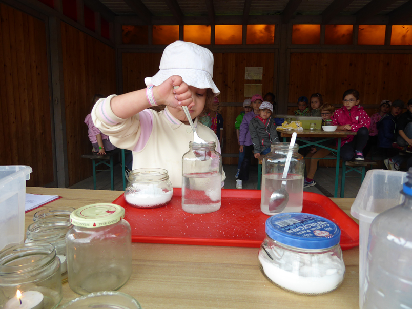 Ein Kind rührt ein weißes Pulver in ein Glas mit Flüssigkeit
