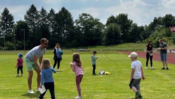 Kinder und Erwachsene auf einem Rasenplatz